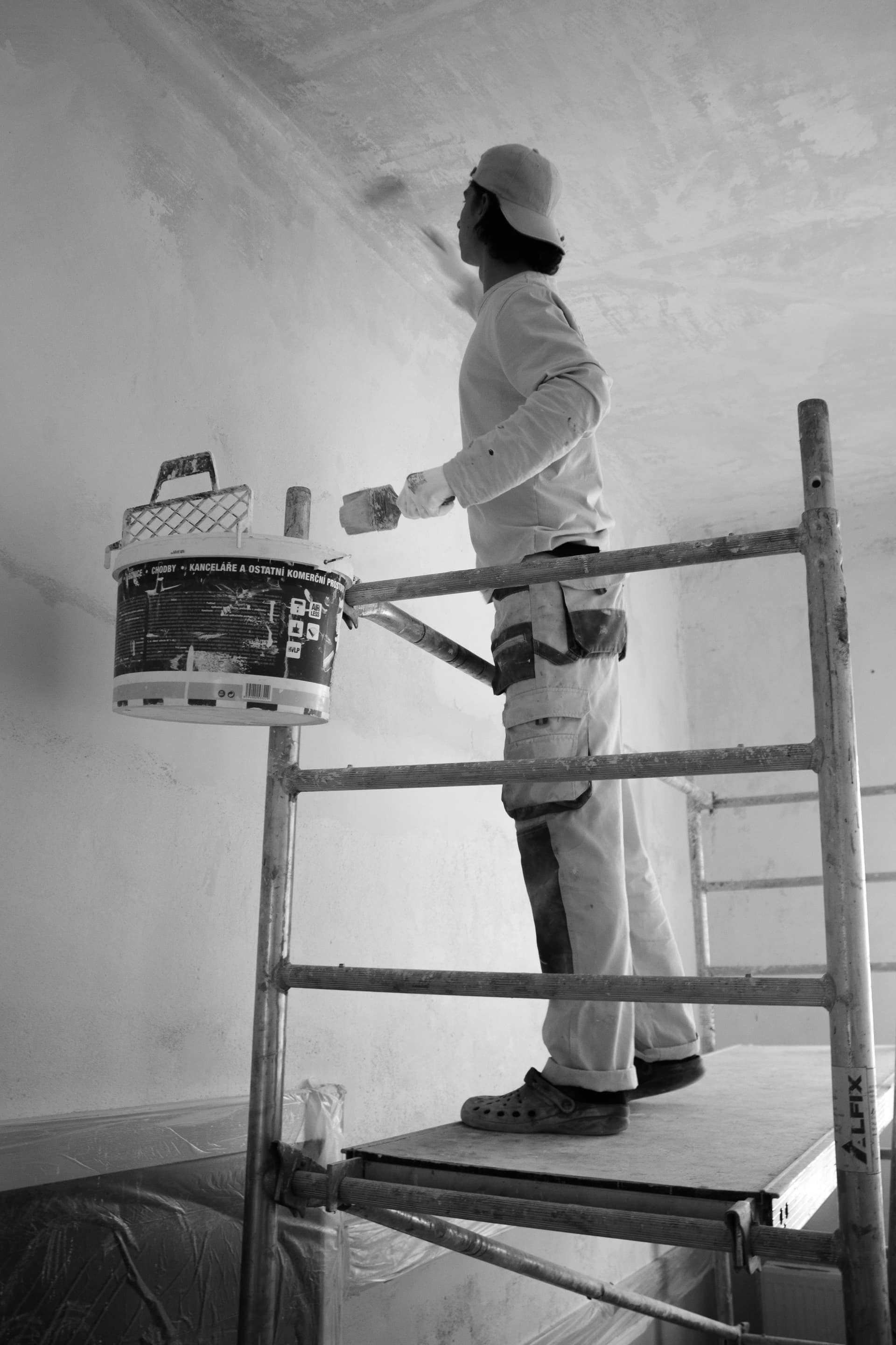 Maler streicht Decke bei Renovierungsarbeiten in einer Wohnung