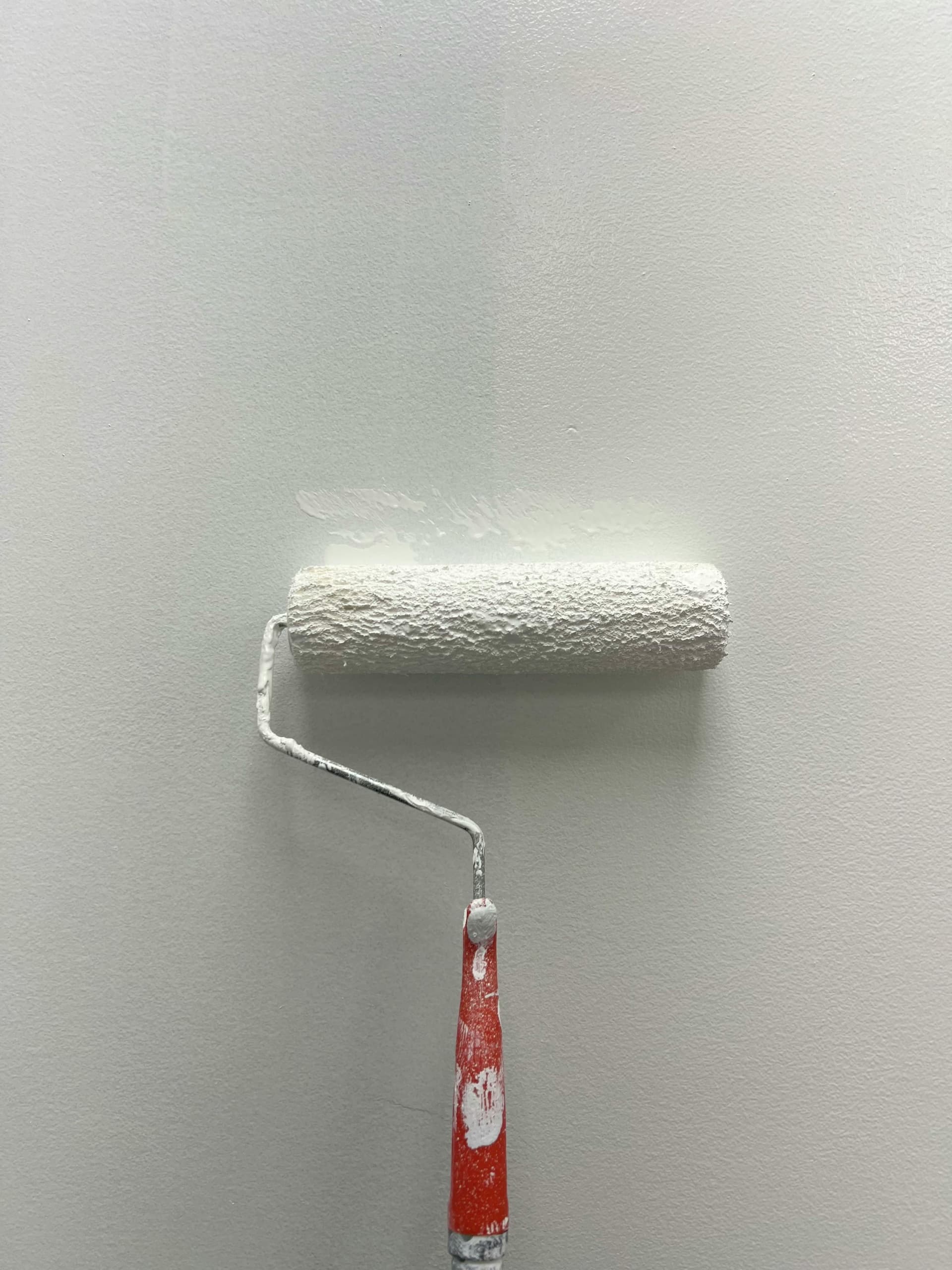 Farbrolle streicht weiße Wand – Renovierungsarbeiten in der Wohnung